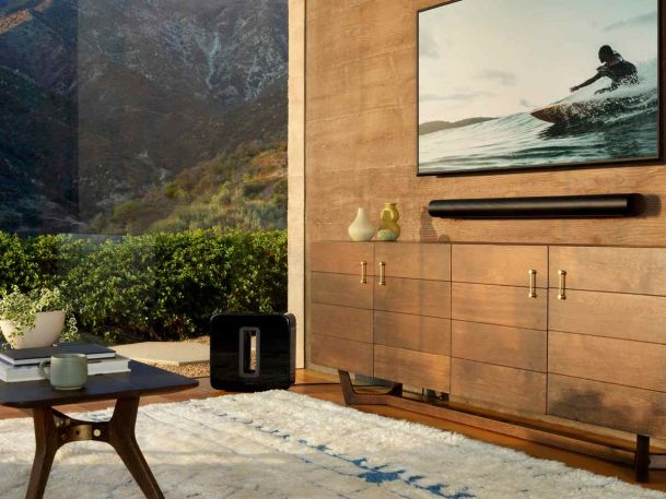 Wall-mounted TV with soundbar and wireless subwoofer in a modern living room