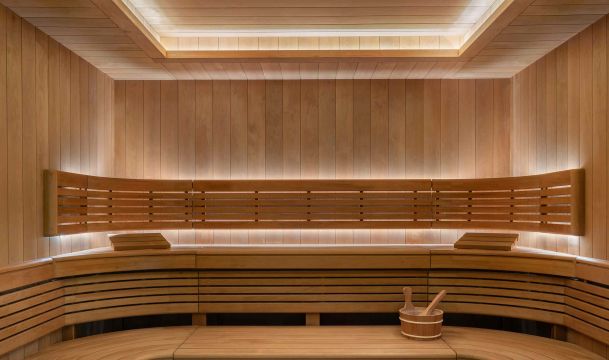 Wood-paneled sauna interior with tiered benches and Lutron warm ambient lighting