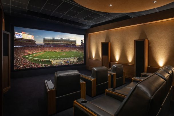 Home theater with leather recliners and a large screen showing a live sporting event