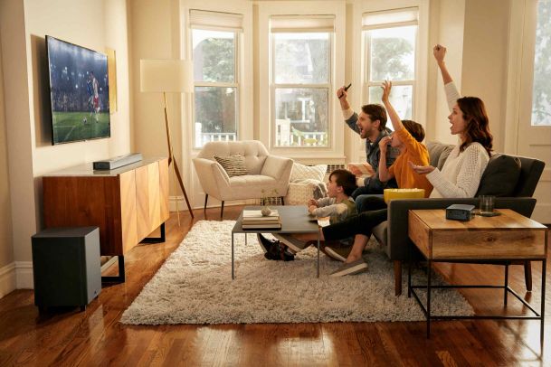 Family cheering while watching sports on a TV with a home surround sound system