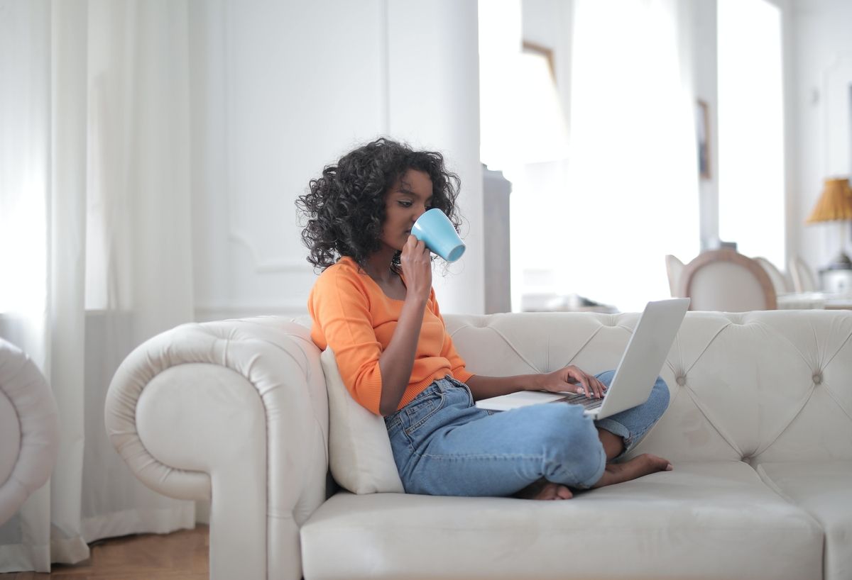 Woman using her computer in the kitchen counter drinking a glass of milk